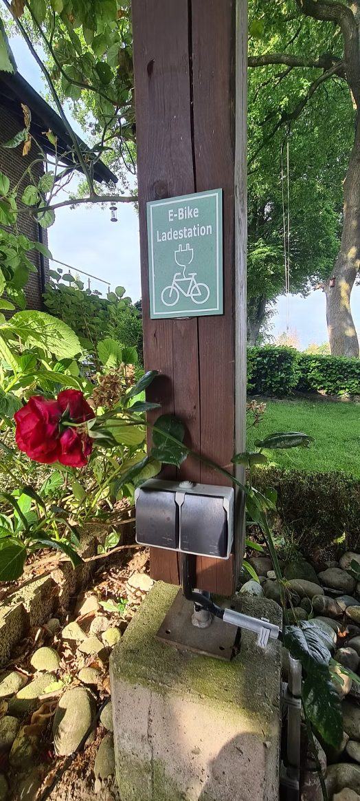 E-Bike-Ladestation mit Doppelsteckdose an einem Holzpfosten im Garten